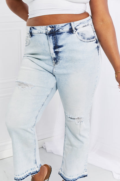 Woman in retro-inspired acid wash jeans, featuring a trendy straight cut and worn-in look for effortless chic.