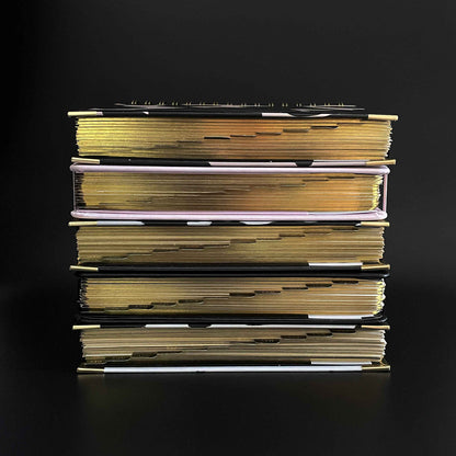 set of 5 2023 daily planners stacked on top of each other showing the tabbed sections