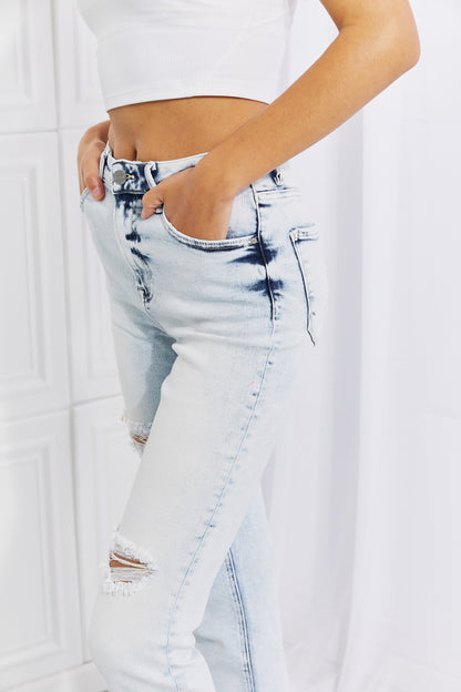 Woman wearing flattering acid wash straight cut jeans, showcasing trendy and timeless style with slight distressing and a casual vibe.