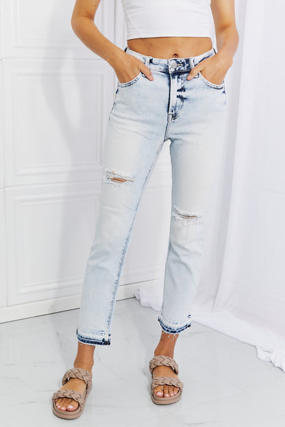 Woman wearing flattering acid wash straight cut jeans, showcasing trendy and timeless style with slight distressing and a casual vibe.