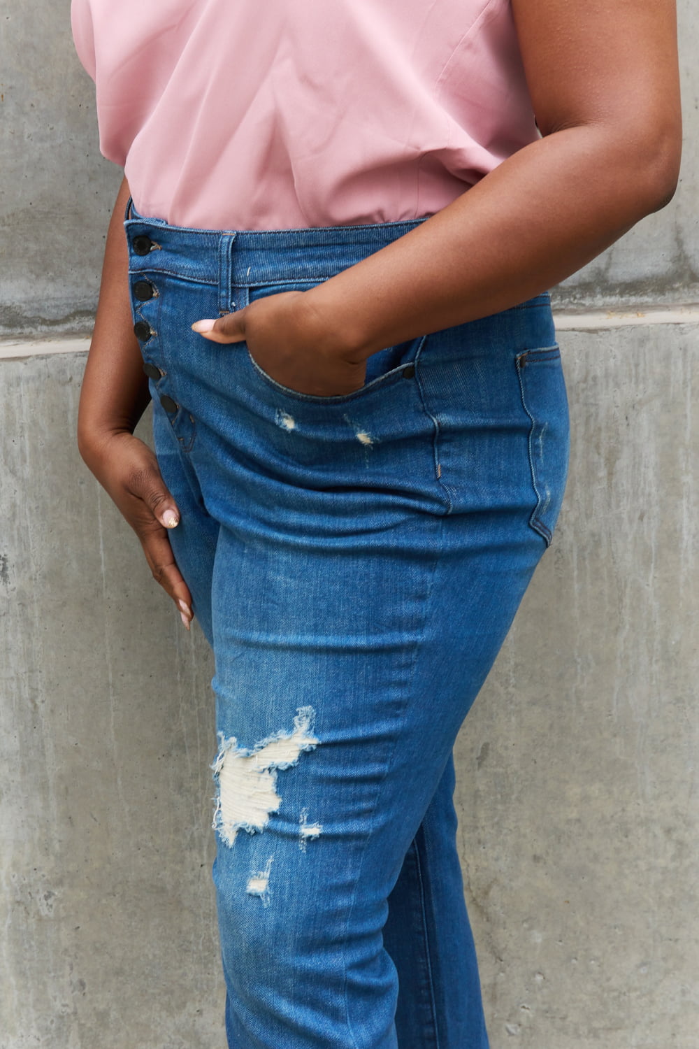 A woman experiencing chic and edgy style with Judy Blue Melanie Full Size High Waisted Distressed Boyfriend Jeans. The jeans showcase a high-waisted design and a trendy distressed look, making a fashionable statement. Made with quality denim, they guarantee both comfort and durability. The relaxed fit adds a touch of casual charm, ideal for everyday wear. 