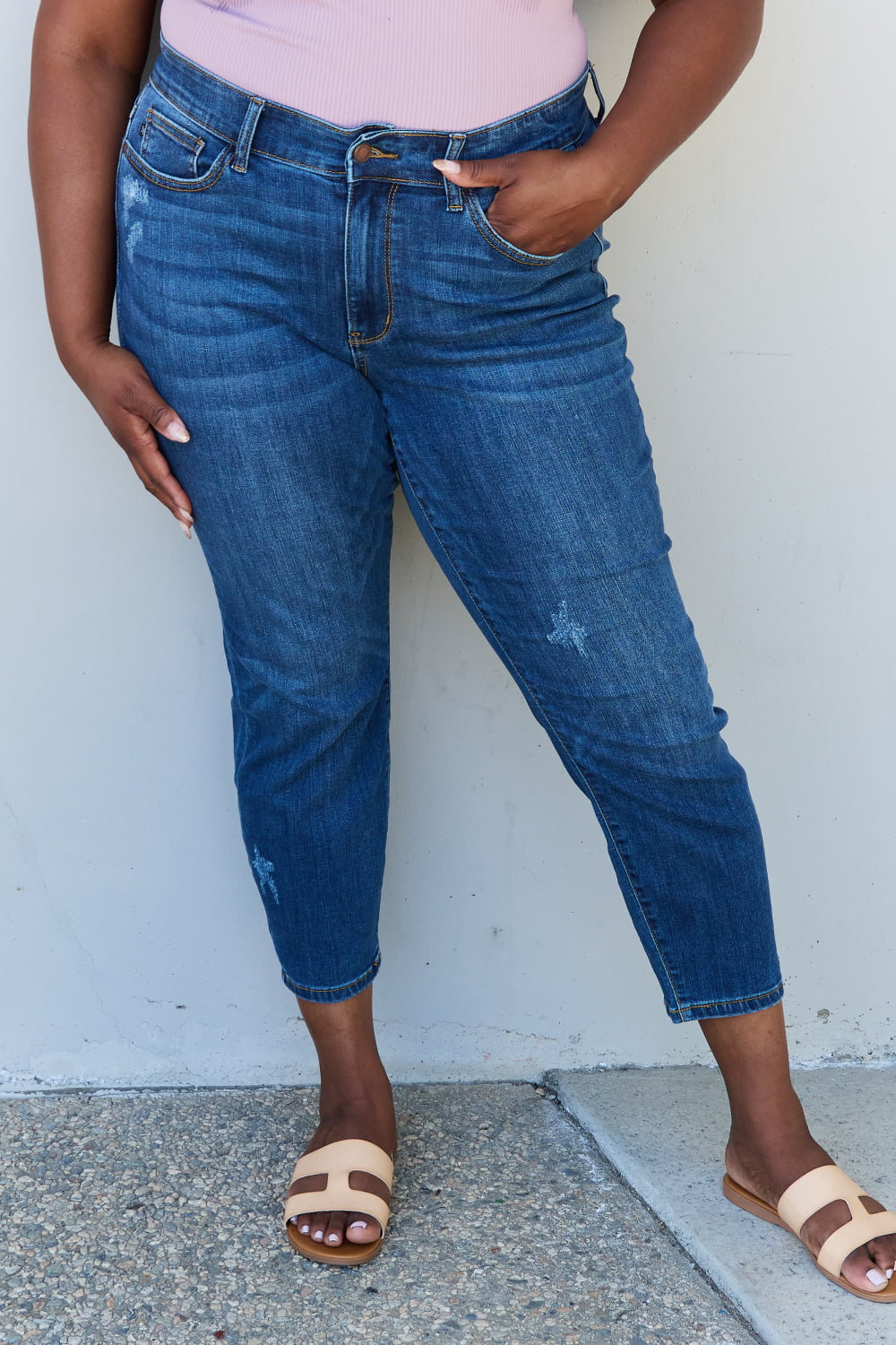 A woman wearing Judy Blue Aila Regular Mid Rise Cropped Relax Fit Jeans, exuding casual chic style. The jeans offer a relaxed fit and feature a flattering mid-rise waist, providing comfortable everyday wear. Their cropped length adds a modern touch, allowing for a showcase of your favorite footwear.
