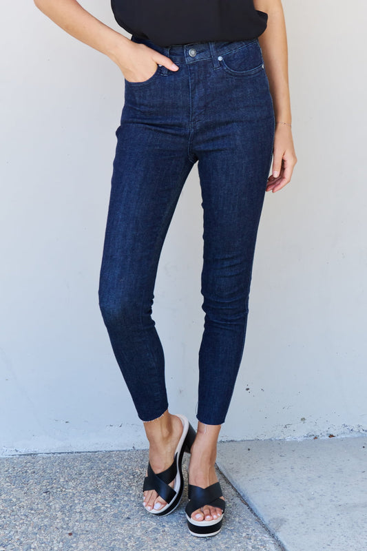 A woman embracing sleek sophistication with Judy Blue Esme Full Size High Waist Skinny Jeans. The jeans feature a high-waisted design that flatters her silhouette and creates a fashionable look. Made from premium denim, they offer a comfortable and flexible fit.