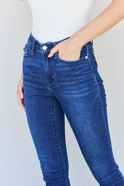 A woman stepping into effortless edge with Judy Blue Marie Full Size Mid Rise Crinkle Ankle Detail Skinny Jeans. The jeans showcase a mid-rise design and crinkle ankle detailing, adding a unique and stylish touch. Made with quality denim, they promise both comfort and durability. 